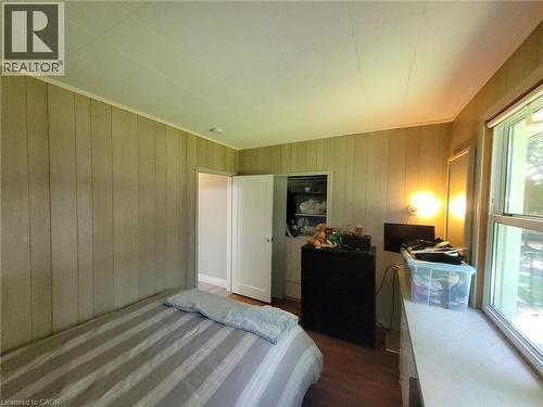 Room featuring vertical wood paneling, wood-finish flooring, a double window, and a built-in closet with bi-fold doors - 879 West 5Th Street, Hamilton, ON - Indoor Photo Showing Bedroom