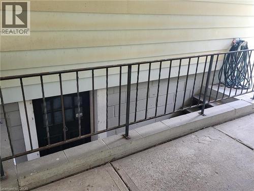 Exterior lower-level entry featuring a security door, concrete block foundation, and an exterior metal railing - 879 West 5Th Street, Hamilton, ON - Outdoor With Exterior