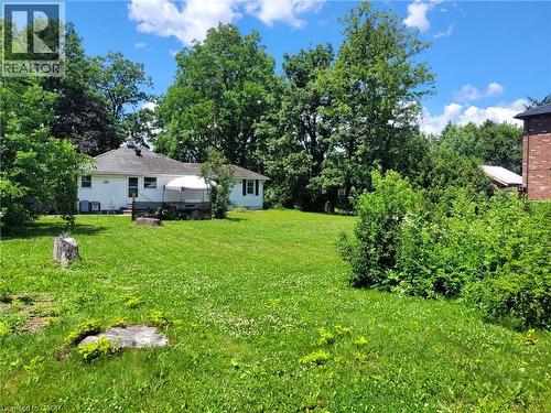 Expansive green lawn with mature trees and a detached single-story residence featuring white siding and dark shutters - 879 West 5Th Street, Hamilton, ON - Outdoor
