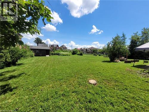Expansive green space featuring a large lawn area, mature perimeter foliage, and a detached outbuilding - 879 West 5Th Street, Hamilton, ON - Outdoor