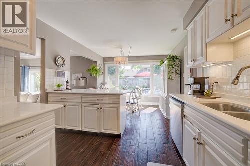 Kitchen featuring white cabinetry, light-colored countertops, dark wood-finish flooring, and a stainless steel double-basin sink - 41 Mcniven Road, Ancaster, ON - Indoor Photo Showing Kitchen With Double Sink