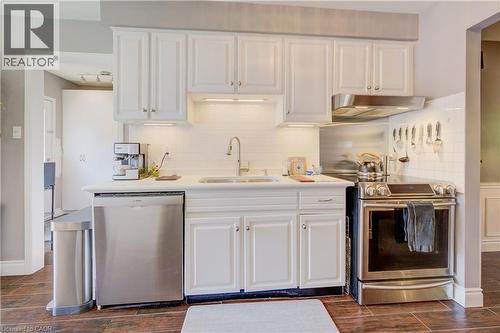 Kitchen showcasing white cabinetry, stainless steel appliances, white subway tile backsplash, and wood-finish flooring - 41 Mcniven Road, Ancaster, ON - Indoor Photo Showing Kitchen With Upgraded Kitchen
