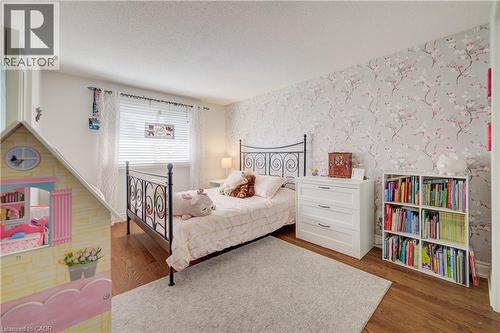 Bedroom featuring wood-finish flooring, a decorative accent wall, and a window with blinds - 41 Mcniven Road, Ancaster, ON - Indoor Photo Showing Bedroom