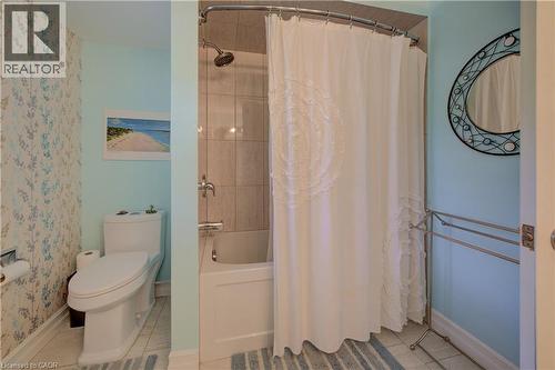 Bathroom featuring a standard bathtub with an overhead shower, light-toned ceramic tile surround, and a wall-mounted towel bar - 41 Mcniven Road, Ancaster, ON - Indoor Photo Showing Bathroom