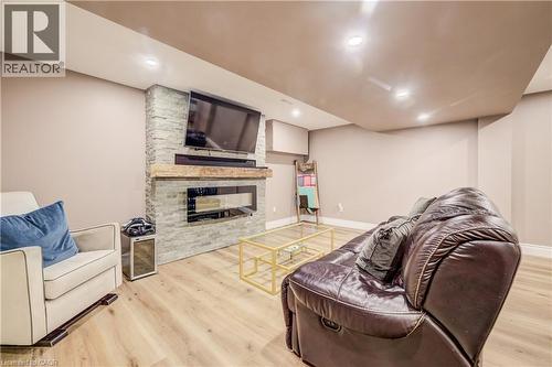 Stone-clad fireplace feature wall with a linear electric fireplace and wood mantel - 41 Mcniven Road, Ancaster, ON - Indoor Photo Showing Basement With Fireplace