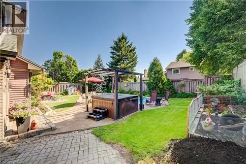 Expansive backyard featuring a hot tub with pergola, paved patio, manicured lawn, and mature perimeter trees - 41 Mcniven Road, Ancaster, ON - Outdoor