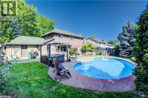 Expansive backyard featuring an in-ground swimming pool with surrounding hardscaping, a hot tub under a pergola, a manicured lawn, and mature trees - 41 Mcniven Road, Ancaster, ON - Outdoor With In Ground Pool With Backyard