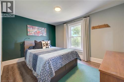 Bedroom featuring a window with white trim, wood-finish flooring, recessed ceiling light, and a dark accent wall - 39 Kerr Street, Cambridge, ON - Indoor Photo Showing Bedroom