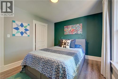 Bedroom featuring wood-finish flooring, a bright window, and a contrasting accent wall - 39 Kerr Street, Cambridge, ON - Indoor Photo Showing Bedroom
