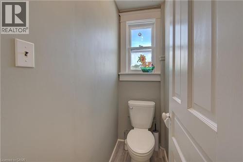 Bathroom featuring a standard white toilet, a window with white trim, and wood-finish flooring - 39 Kerr Street, Cambridge, ON - Indoor Photo Showing Bathroom