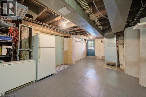 Finished basement space featuring exposed ceiling joists, overhead lighting, an exterior door with glass panes, and a concrete foundation wall - 39 Kerr Street, Cambridge, ON - Indoor Photo Showing Basement