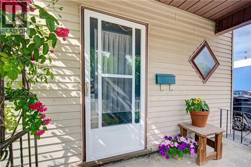 Entryway featuring a white storm door, beige horizontal siding, and a decorative diamond-shaped window - 39 Kerr Street, Cambridge, ON - Outdoor With Deck Patio Veranda With Exterior