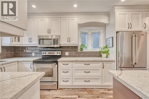 Kitchen featuring white shaker cabinetry, light-toned countertops, stainless steel appliances, and wood-finish flooring - 851 Beach Boulevard, Hamilton, ON - Indoor Photo Showing Kitchen
