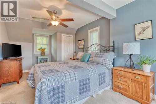 Bedroom featuring a decorative metal bed frame, light blue and gray wall tones, two windows with white trim, a built-in ceiling fan with light fixture, and a white paneled door - 851 Beach Boulevard, Hamilton, ON - Indoor Photo Showing Bedroom