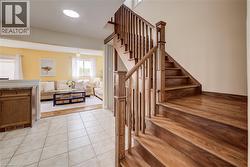 Hardwood staircase with natural wood railings, offering a visual separation from the living area with light yellow walls and multiple windows - 