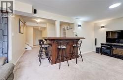 Lower level featuring a built-in bar, recessed lighting, wall-mounted light fixtures, carpet flooring, and a French door entry - 