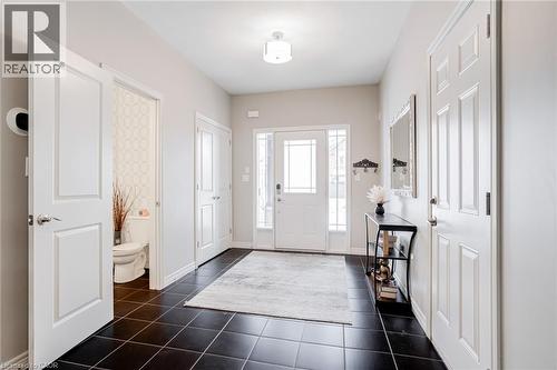 Entry foyer featuring dark square floor tiles, a white front door with decorative glass inserts, and an overhead flush-mount light fixture - 7 Kinsman Drive, Binbrook, ON - Indoor Photo Showing Other Room