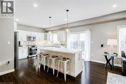 Kitchen featuring white cabinetry, stainless steel appliances, a tile backsplash, and a central island with countertop seating - 
