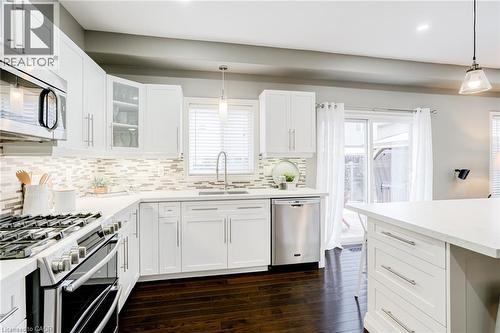 Kitchen featuring white shaker-style cabinetry, stainless steel appliances, mosaic tile backsplash, and dark wood-finish flooring - 7 Kinsman Drive, Binbrook, ON - Indoor Photo Showing Kitchen With Upgraded Kitchen