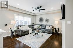 Spacious living area featuring wood-finish flooring, a large window with blinds, recessed lighting, and a ceiling fan - 