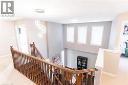Upper-level landing featuring a contemporary chandelier and carpeted flooring - 