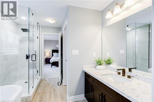 Bathroom featuring a dark wood-finish vanity with a light-toned countertop, a frameless mirror, and a glass-enclosed shower with marble-look tile - 7 Kinsman Drive, Binbrook, ON - Indoor Photo Showing Bathroom