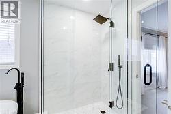 Glass-enclosed shower featuring large format white tile walls, a rain shower head, and an additional handheld shower fixture - 