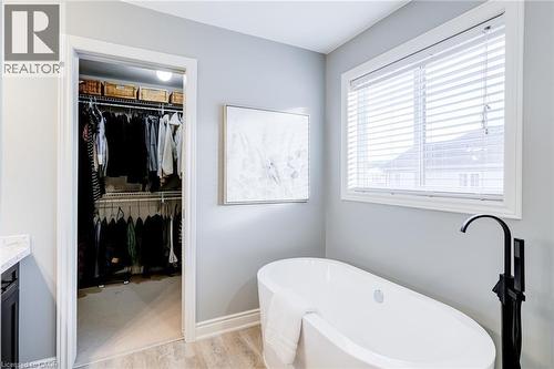 Freestanding soaking tub with a matte black floor-mounted faucet, complemented by light wood-finish flooring - 7 Kinsman Drive, Binbrook, ON - Indoor Photo Showing Bathroom