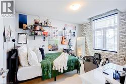 Bedroom featuring a large window with blinds, a white brick-patterned accent wall, and built-in wall shelving - 