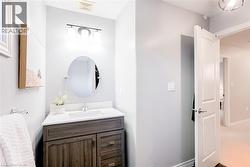 Powder room featuring a wood-finish vanity with drawer and cabinet storage, a white countertop with an integrated sink, and an oval mirror - 