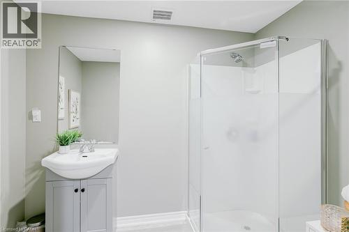 Bathroom featuring a glass-enclosed shower, a vanity with a white ceramic sink, a rectangular wall-mounted mirror, and light-toned walls - 7 Kinsman Drive, Binbrook, ON - Indoor Photo Showing Bathroom