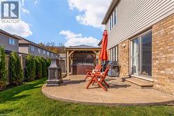 Outdoor stamped concrete patio featuring a gazebo, hot tub, and exterior fireplace - 