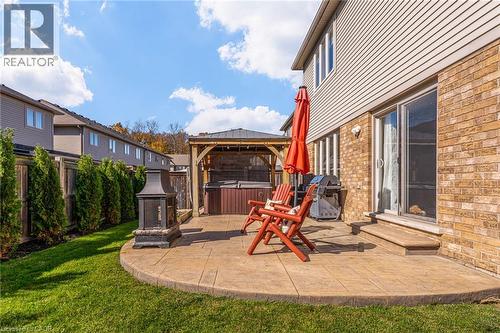 Outdoor stamped concrete patio featuring a gazebo, hot tub, and exterior fireplace - 7 Kinsman Drive, Binbrook, ON - Outdoor With Deck Patio Veranda