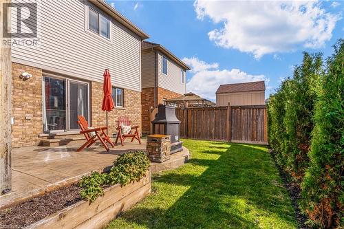 Rear yard featuring a stamped concrete patio, sliding glass door access, and a built-in stone fire pit - 7 Kinsman Drive, Binbrook, ON - Outdoor With Deck Patio Veranda