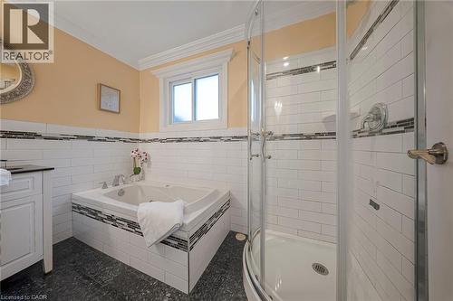 Bathroom featuring a corner soaking tub with mosaic tile accents, a separate glass-enclosed shower, subway tile surround, and dark-finish flooring - 124 Dunsmere Drive, Kitchener, ON - Indoor Photo Showing Bathroom