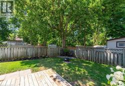 Expansive backyard featuring a wood deck, a manicured lawn, and a privacy fence - 