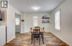Spacious room featuring wood-finish flooring, white baseboards, and two windows with blinds - 