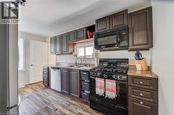 Kitchen with wood-finish flooring, dark wood-tone cabinetry, and speckled laminate countertops - 