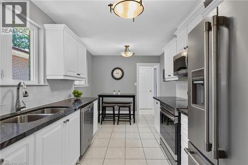 Galley kitchen featuring white cabinetry, dark countertops, stainless steel appliances, tile flooring, and recessed ceiling lighting - 1172 Chada Avenue, Mississauga, ON - Indoor Photo Showing Kitchen With Stainless Steel Kitchen With Double Sink