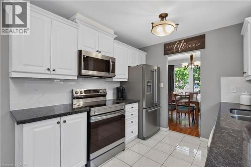 Kitchen featuring white cabinetry with crown molding, stainless steel appliances, dark stone countertops, and white tile flooring - 1172 Chada Avenue, Mississauga, ON - Indoor Photo Showing Kitchen With Stainless Steel Kitchen With Double Sink