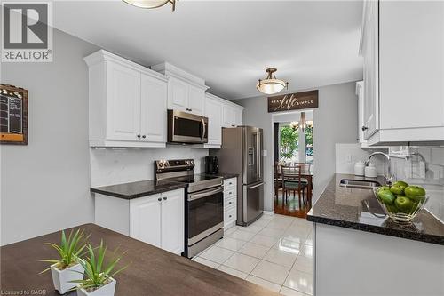 Kitchen featuring white cabinetry, dark countertops, a tile backsplash, and stainless steel appliances - 1172 Chada Avenue, Mississauga, ON - Indoor Photo Showing Kitchen With Stainless Steel Kitchen With Double Sink