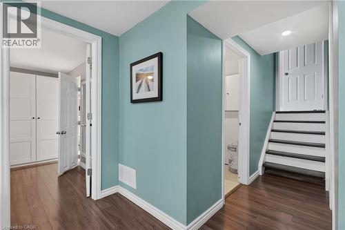 Hallway featuring rich wood-finish flooring, light teal wall paint, white trim, and a white staircase with dark treads - 1172 Chada Avenue, Mississauga, ON - Indoor Photo Showing Other Room
