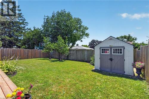 Expansive green lawn featuring a storage shed with double doors, wood fencing, mature trees, and a partial wood deck - 1172 Chada Avenue, Mississauga, ON - Outdoor