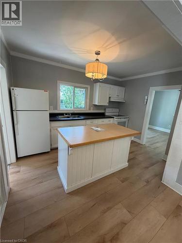 Kitchen featuring a central island with wood countertop, light wood-finish flooring, white cabinetry, and a window above the sink - 104 Marshall Street, Waterloo, ON - Indoor Photo Showing Kitchen
