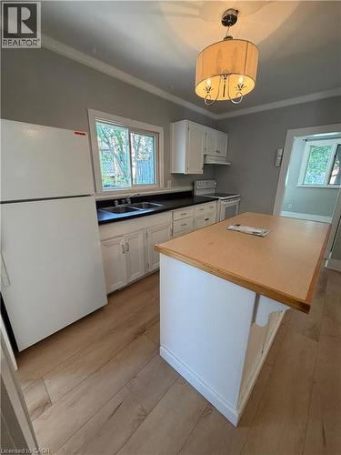 Kitchen featuring an island with wood-finish countertop, white cabinetry, and wood-finish flooring - 104 Marshall Street, Waterloo, ON - Indoor Photo Showing Kitchen With Double Sink