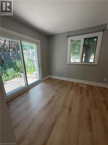 Light wood-finish flooring with a sliding glass door and an additional window providing exterior visibility - 104 Marshall Street, Waterloo, ON - Indoor Photo Showing Other Room