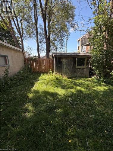 Enclosed yard area featuring a wooden shed with a window, a wooden privacy fence, and mature trees providing natural shade - 104 Marshall Street, Waterloo, ON - Outdoor