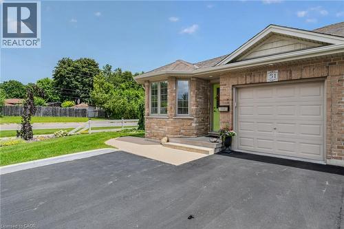 Brick and stone exterior featuring an integrated single-car garage, a bay window, a vibrant green entry door, and a paved driveway - 51 Millcroft Drive, Simcoe, ON - Outdoor
