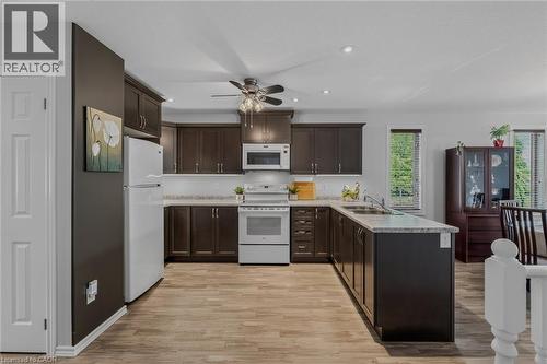 Kitchen featuring dark wood-finish cabinetry, light-toned countertops, and a white subway tile backsplash - 51 Millcroft Drive, Simcoe, ON - Indoor Photo Showing Kitchen With Double Sink