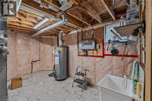 Unfinished basement featuring exposed wood joists, a water heater, electrical panel, utility sink, and concrete flooring - 51 Millcroft Drive, Simcoe, ON - Indoor Photo Showing Basement